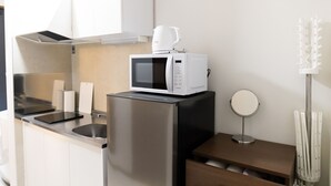 A compact kitchen with a microwave, a kettle, a sink, and a small round mirror. - Marina Sunrise Osaka Bay Annex (Osaka)