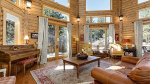 A log cabin interior with a piano, sofa, and dining area.