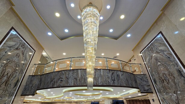 Un vaste hall d’entrée agrémenté d’un grand lustre, de murs en marbre et d’un plafond cintré.