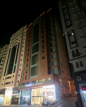 Et flere etagers hotel med en moderne facade, store vinduer og butikslokaler i stueetagen.