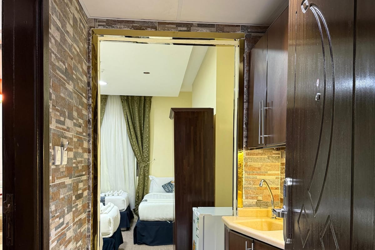 A hotel room with a bed, a small kitchenette, and a bathroom.