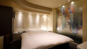 A hotel room with a large bed, a wardrobe, and a wall with abstract art. - HOTEL ROYALTON (Nagoya)