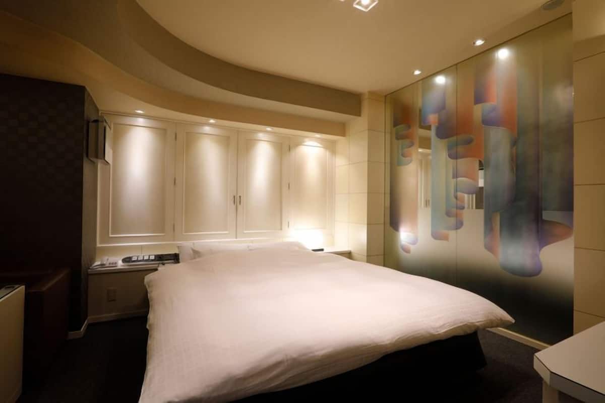 Habitación de hotel con una cama grande, un armario y una pared decorada con arte abstracto.