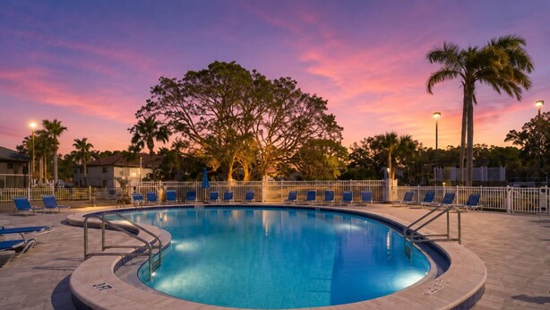 A swimming pool with lounge chairs and palm trees at sunset. - Bradenton Beach Condo -2 Pools- 15 minutes to Anna Maria Island Beaches-First Floor- End Unit (Bradenton)