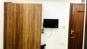 Una habitación con un armario de madera, un televisor montado en la pared y una puerta.