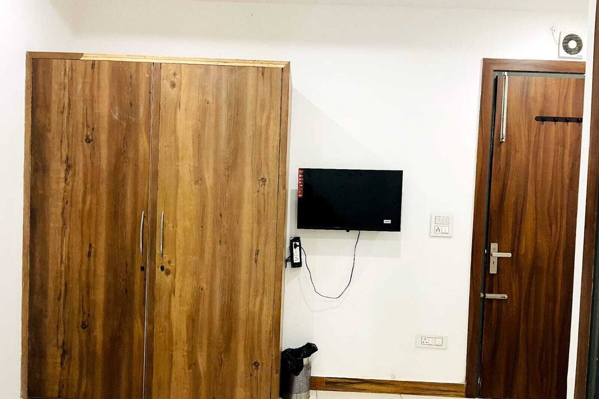 Ein Zimmer mit einem Holzschrank, einem an der Wand befestigten Fernseher und einer Tür.