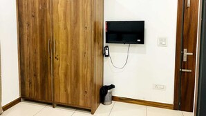 Una habitación con un armario de madera, un televisor de pantalla plana montado y una puerta con picaporte.