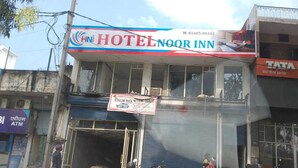 Un hotel llamado "Hni Hotel Noor Inn" con un letrero que anuncia un servicio de alquiler de coches.
