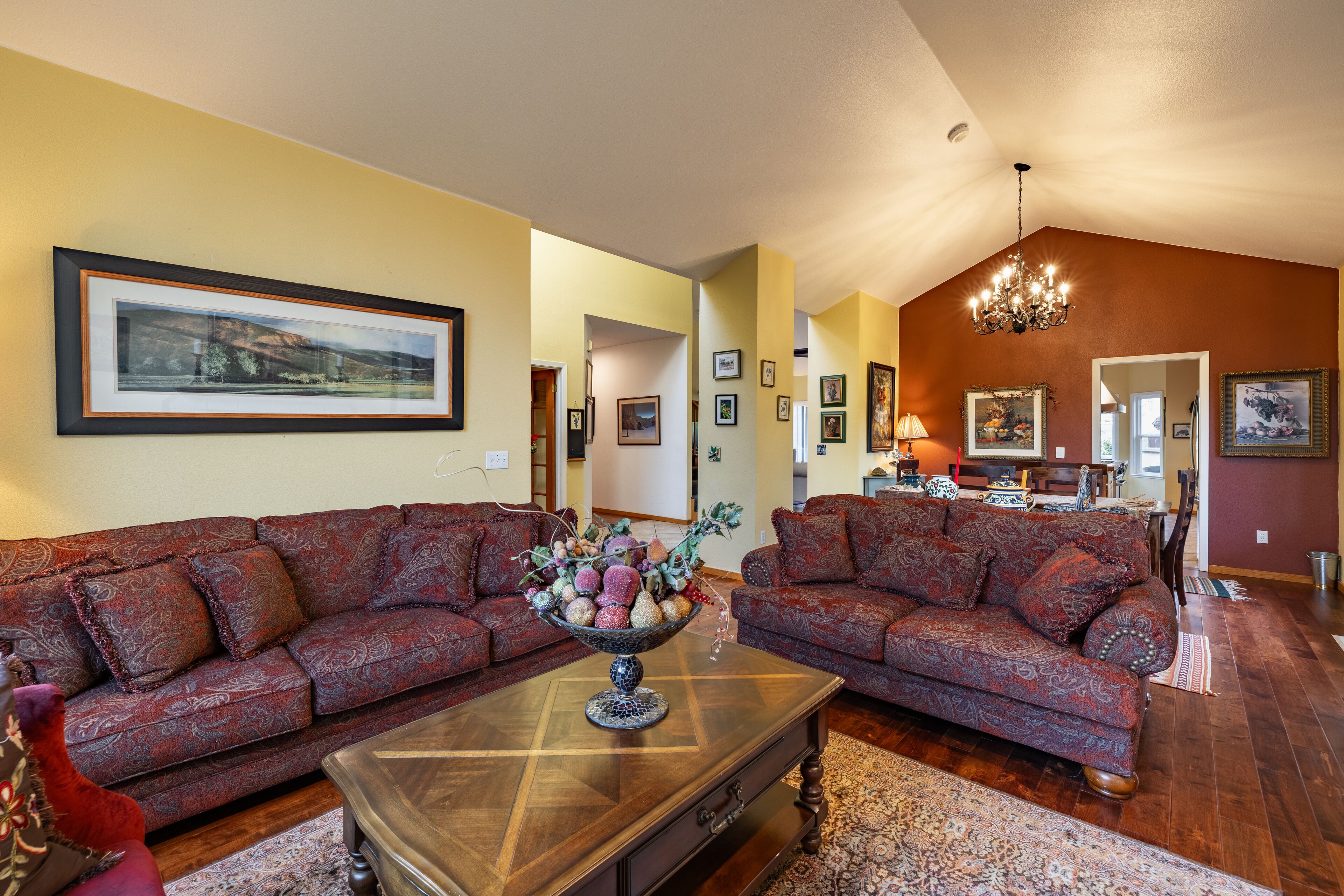 A living room with two patterned sofas, a coffee table with a decorative bowl, and a chandelier.