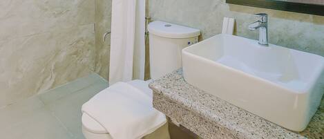 A bathroom with a shower, toilet, sink, and a mirror.