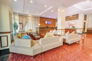 Un vestíbulo de hotel con sofás, una recepción y un gran letrero que dice "Monaco Hotel".