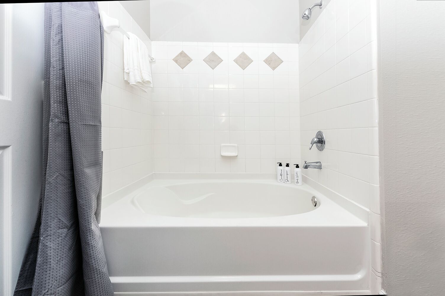 Een badkamer met een wit bad, een douchegedeelte en een handdoekrek met handdoeken.