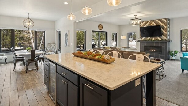 A modern kitchen with a large island, pendant lighting, and a fireplace. - Crescent Moon Retreat (Lead)