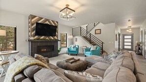 A modern living room with a fireplace, a staircase, and a large sofa. - Crescent Moon Retreat (Lead)