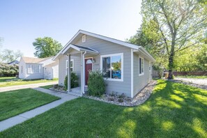 A single-story house with a front porch, a red door, and a mailbox.