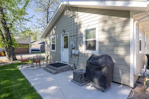 A single-story house with a covered grill, a small patio with chairs, and a garage. - Pet friendly, Privacy Fenced Yard, Hot Tub, 2 bedroom, Cute Canyon Lake House (Rapid City)