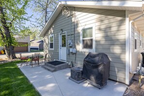 Einbungalow mit überdachter Grillstelle, einer kleinen Terrasse mit Sitzgelegenheiten und einer Garage.
