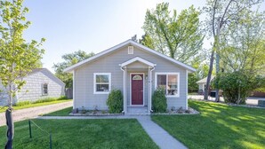 Une maison de plain-pied avec une porte d’entrée, deux fenêtres sur le côté et un petit jardin à l’avant.