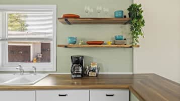 A kitchen with a wooden countertop, a coffee maker, and a window with blinds.