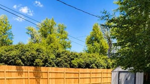 Un bain à remous avec de l’eau en circulation, entouré d’une clôture en bois et d’arbres.