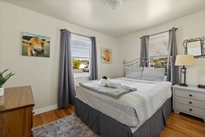 Ein Schlafzimmer mit Bett, Nachttisch, Lampe und Kunstwerk.