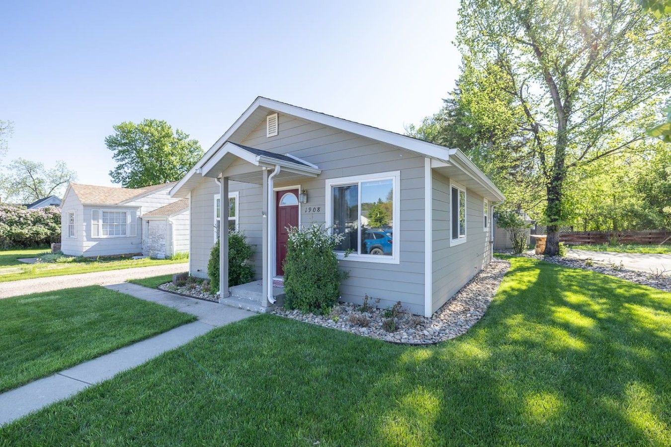 A single-story house with a front porch, a red door, and a mailbox.