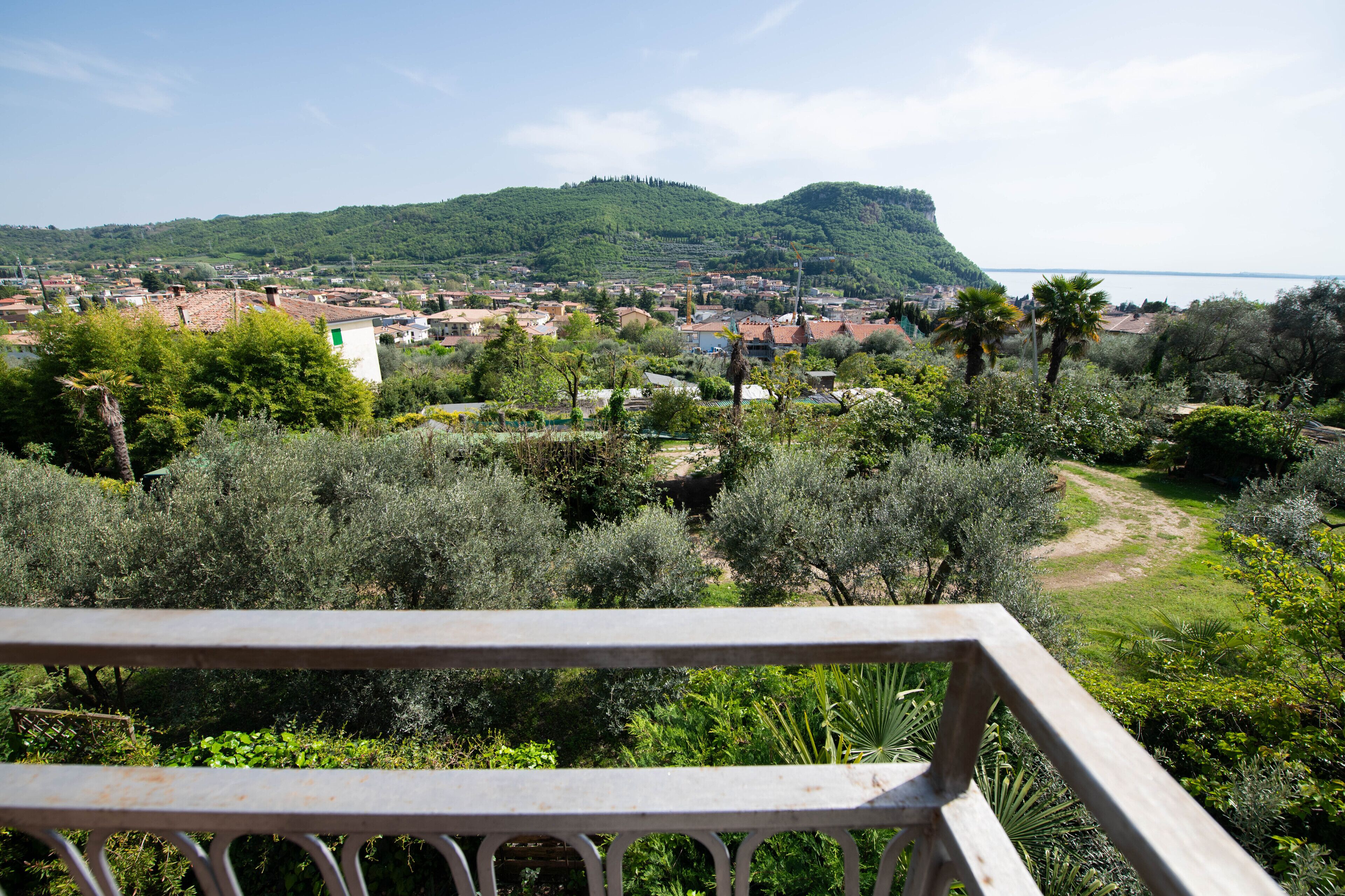 A scenic view of a coastal town with a prominent hill, lush greenery, and a clear sky.