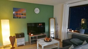 Un salon comprenant un téléviseur, un canapé, une table basse et des objets de décoration.