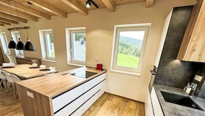 A modern kitchen with a wooden island, white cabinets, and a view of the outdoors.