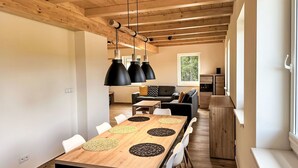A modern dining area with a wooden table, white chairs, and black pendant lights.