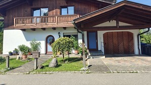 Ein zweigeschossiges Holzhaus mit Balkon, Garage und einem Steinweg, der zum Eingang führt.