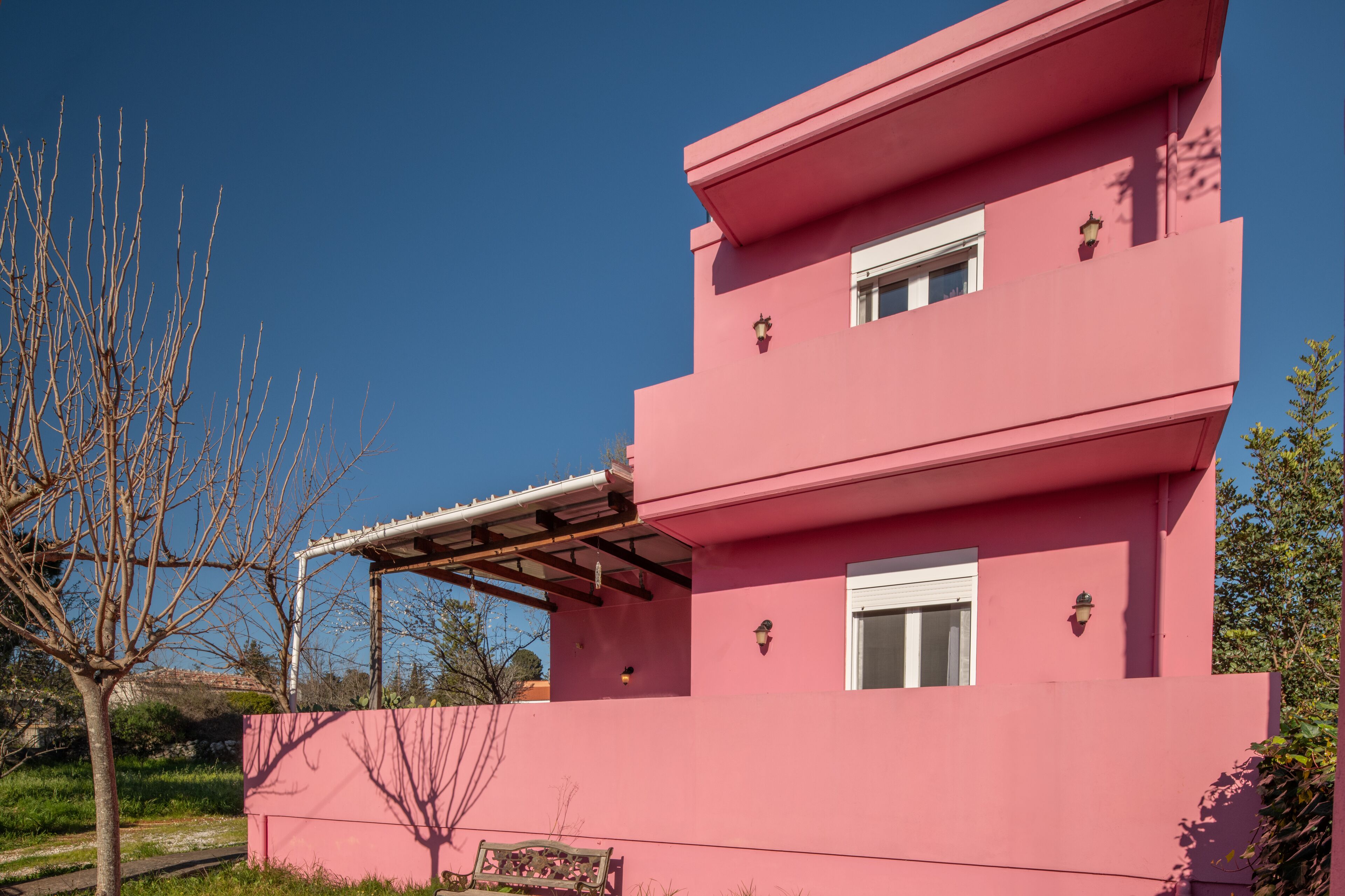 A pink two-story building with a covered patio area and a small garden.