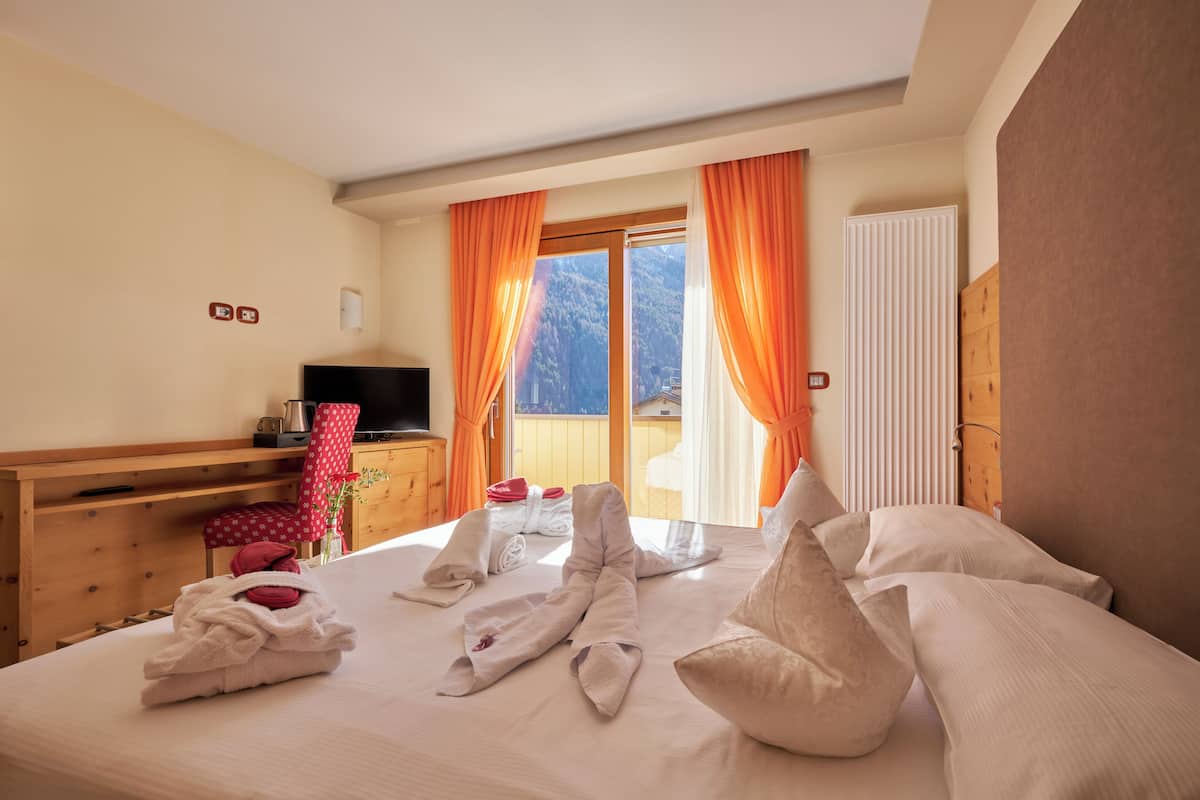 Een hotelkamer met een bed, een televisie, een houten bureau, een stoel en uitzicht op de omgeving.