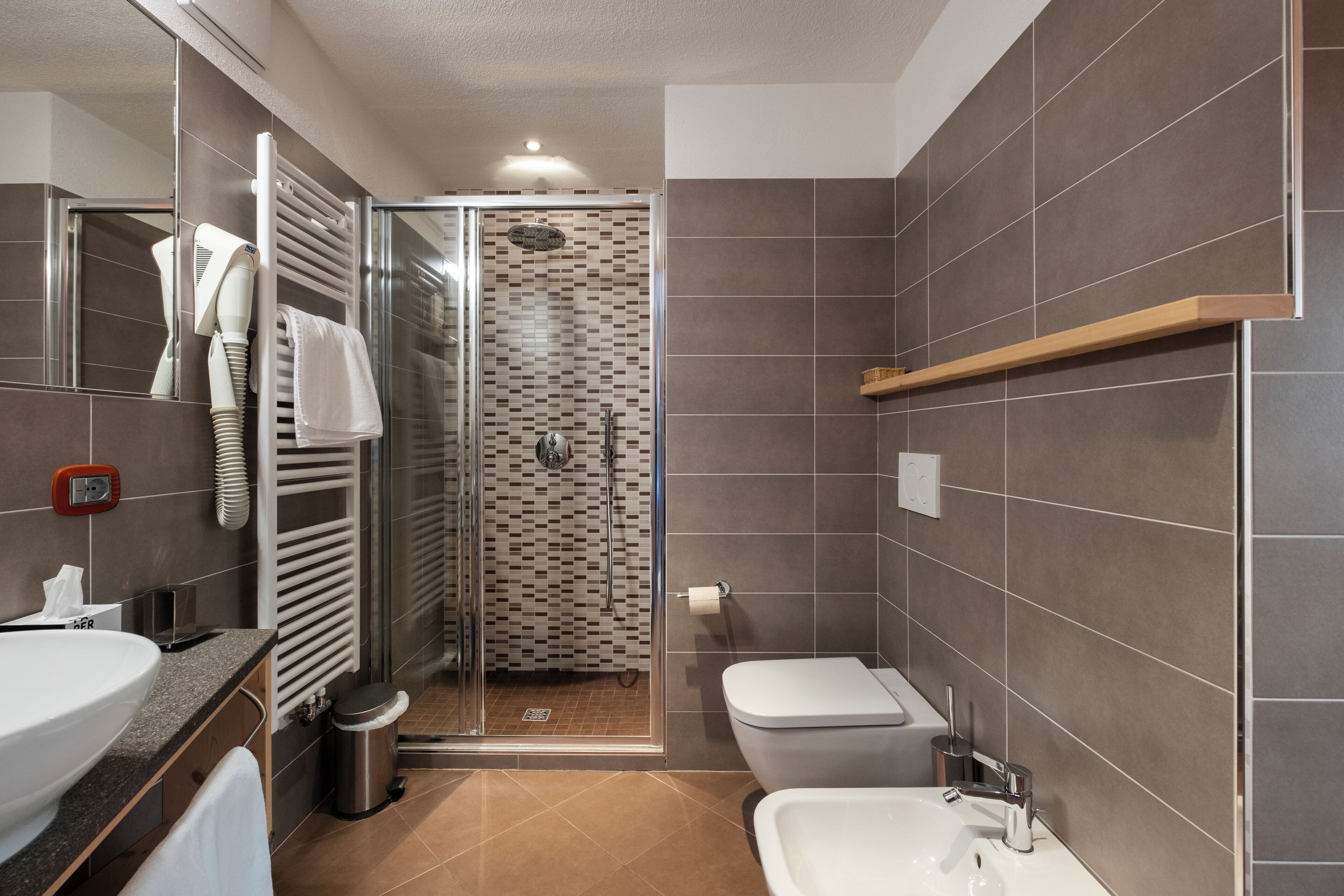 Un baño moderno con ducha vidriada, un lavabo blanco y un inodoro.