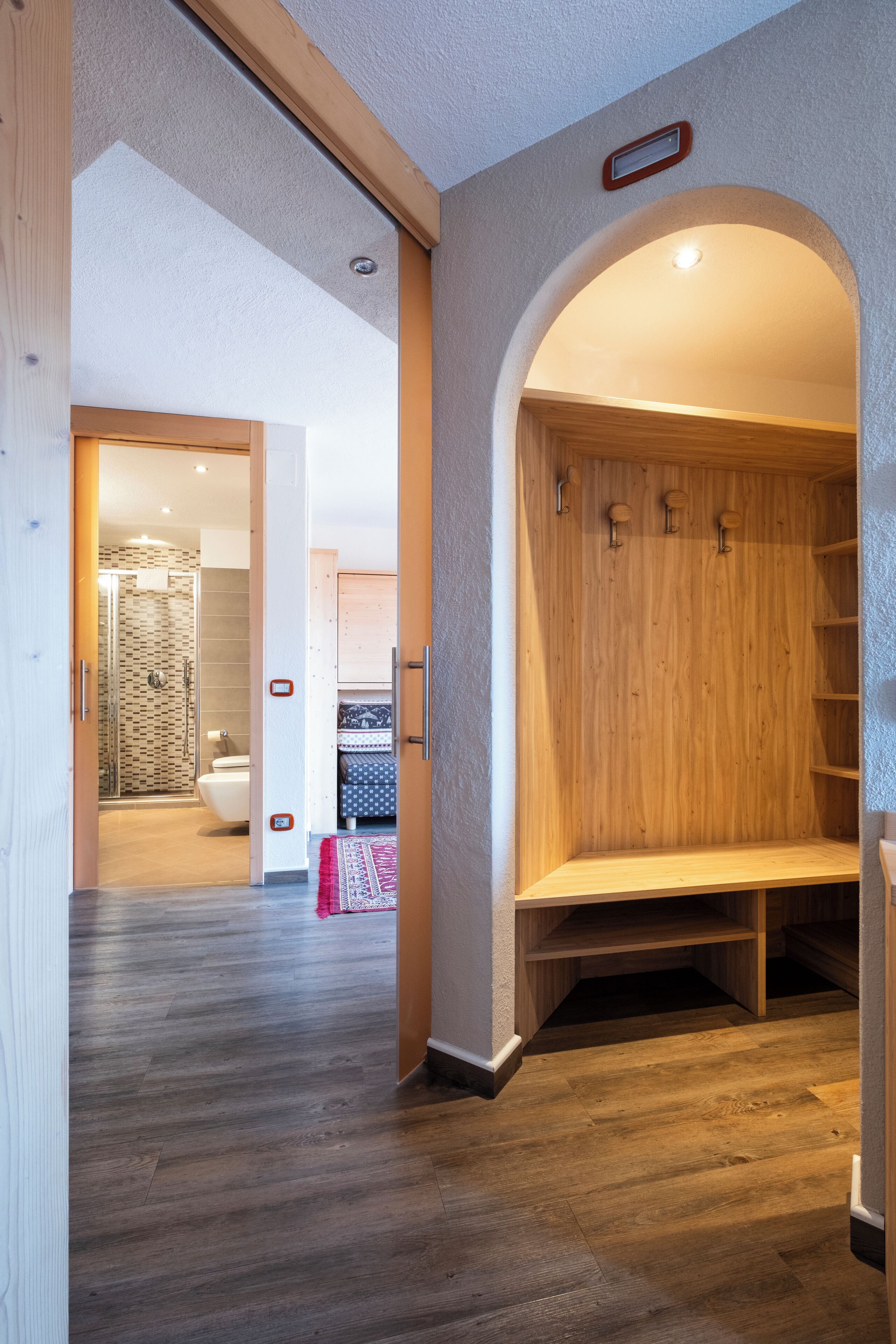 A modern interior with a wooden bench, a shower area, and a visible toilet.