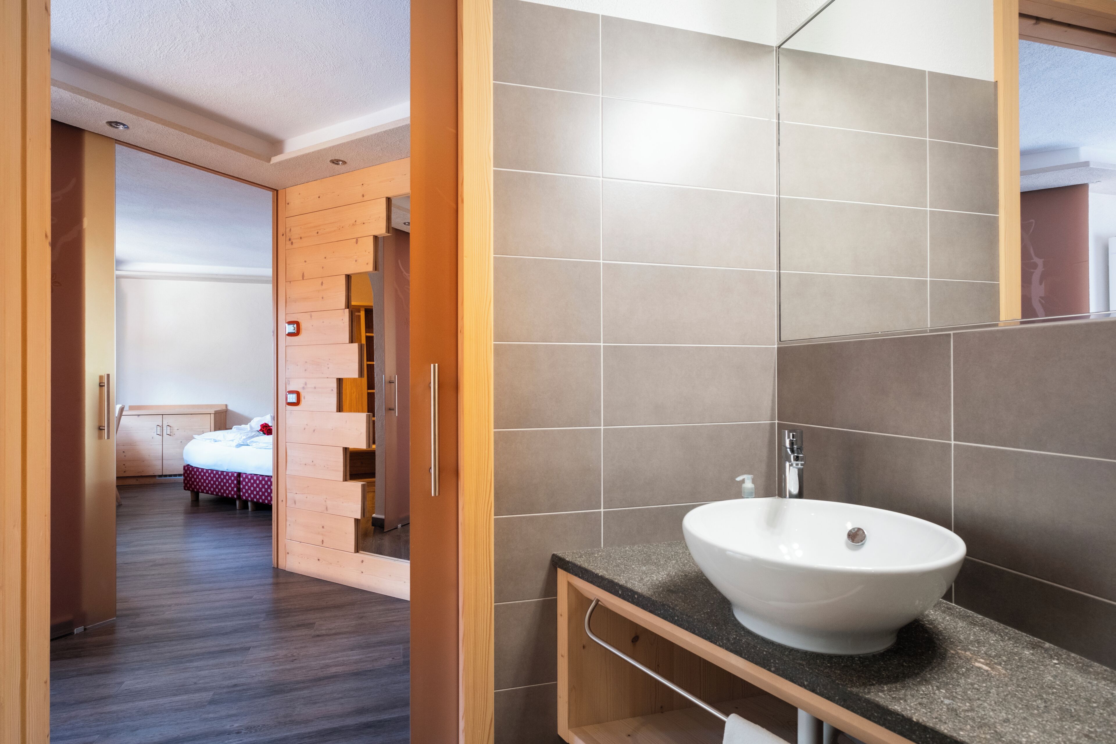 Ein modernes Badezimmer mit einem großen Waschbecken, Holzschränken und einer gefliesten Wand.