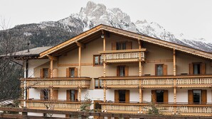 Un edificio de madera de varios pisos con balcones, con una imponente montaña nevada de fondo.