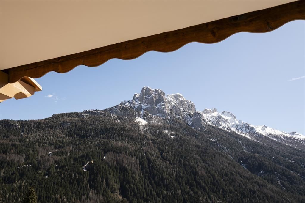 Une montagne dont le sommet est enneigé, recouverte d’une forêt dense, et sur laquelle se trouve une construction en bois dotée d’un toit incurvé.