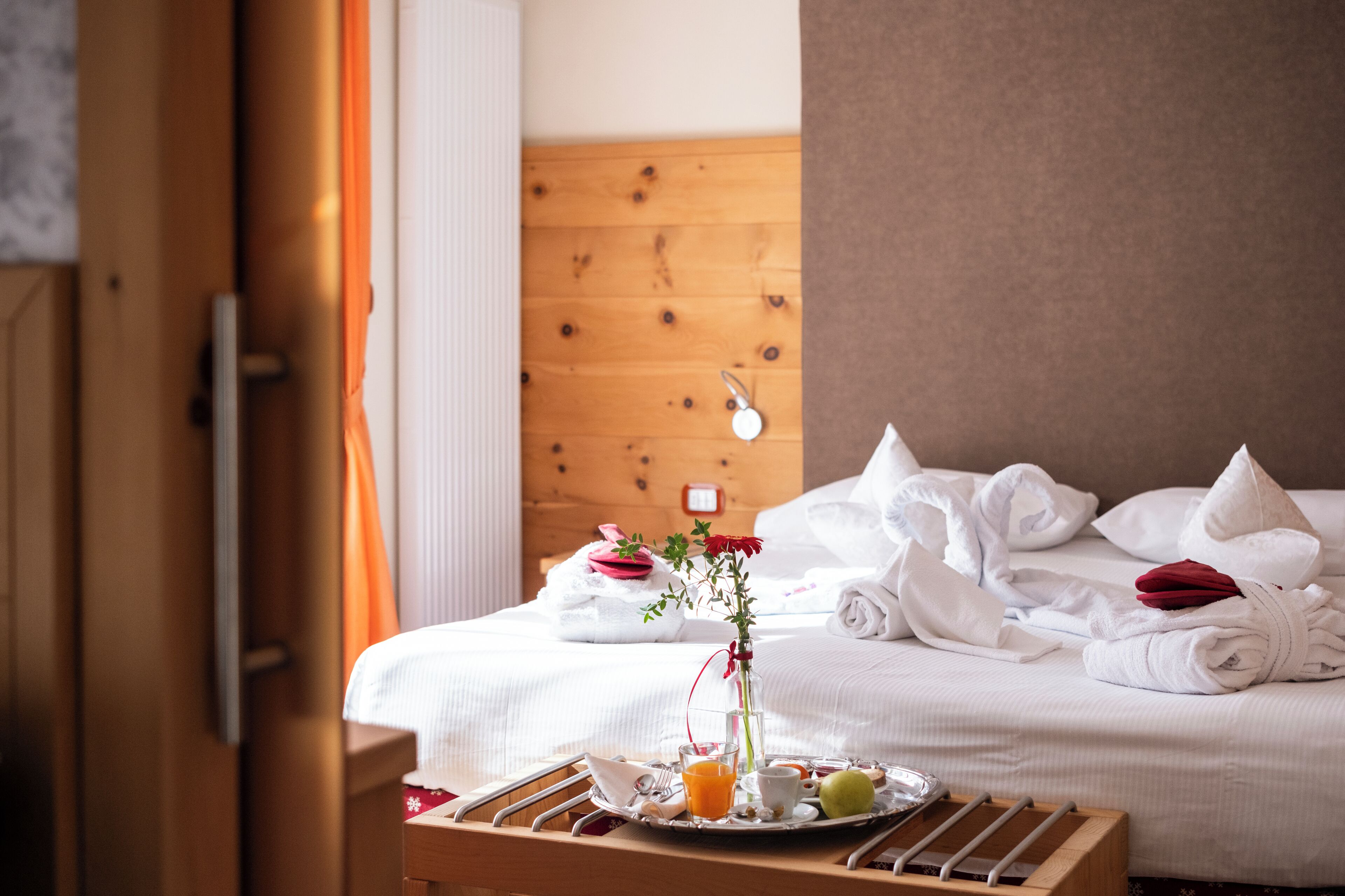 Quarto de hotel com uma cama bem arrumada, um serviço de café da manhã e cabeceira de madeira.