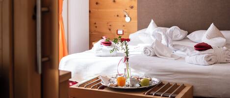 Quarto de hotel com uma cama bem arrumada, um serviço de café da manhã e cabeceira de madeira.