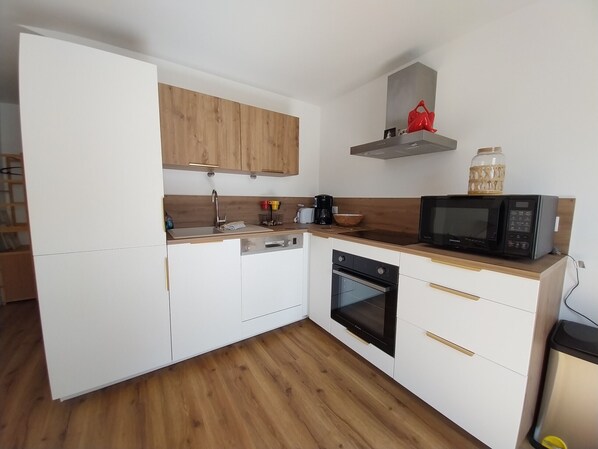 A compact kitchen with white cabinets, a wooden countertop, a microwave, and a coffee maker.
