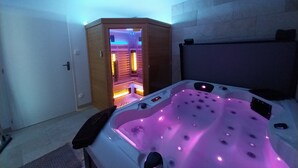 Et værelse med massagestol, træskab og jacuzzi med LED-lys.
