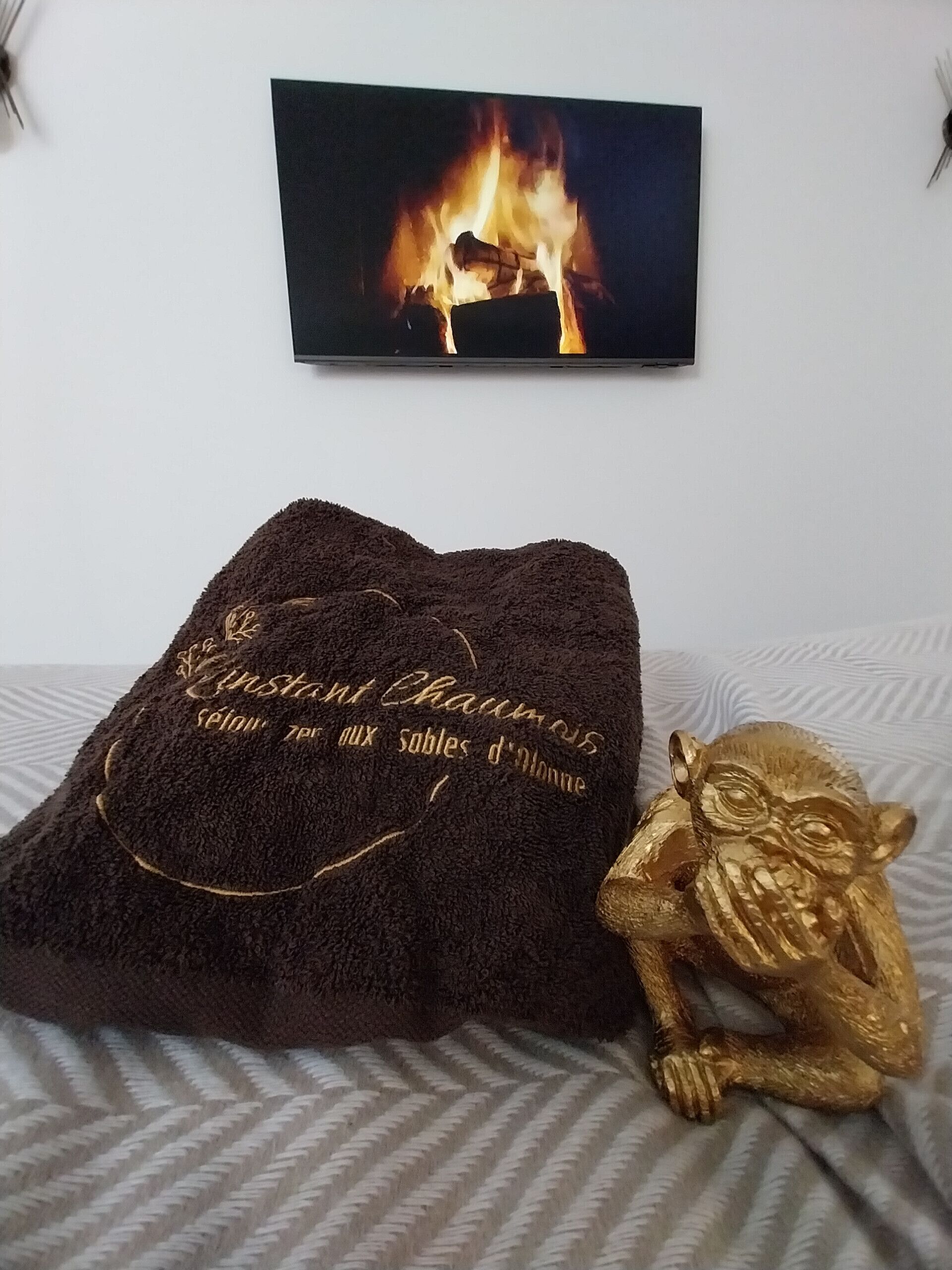 A bed with a dark brown towel and a golden statue on it.