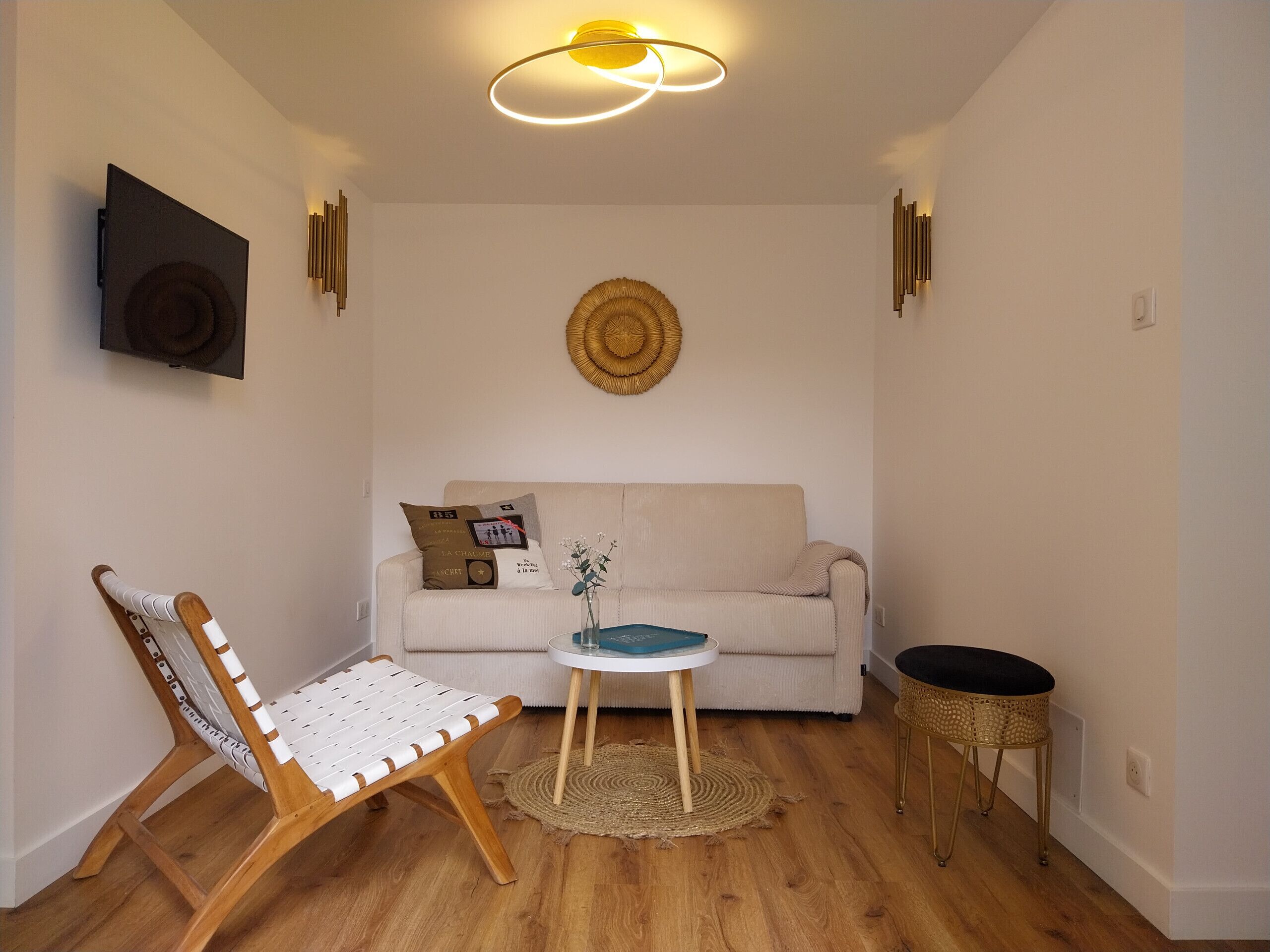 Un soggiorno moderno con un divano, una sedia in legno, un tavolino rotondo e un elemento decorativo a parete.