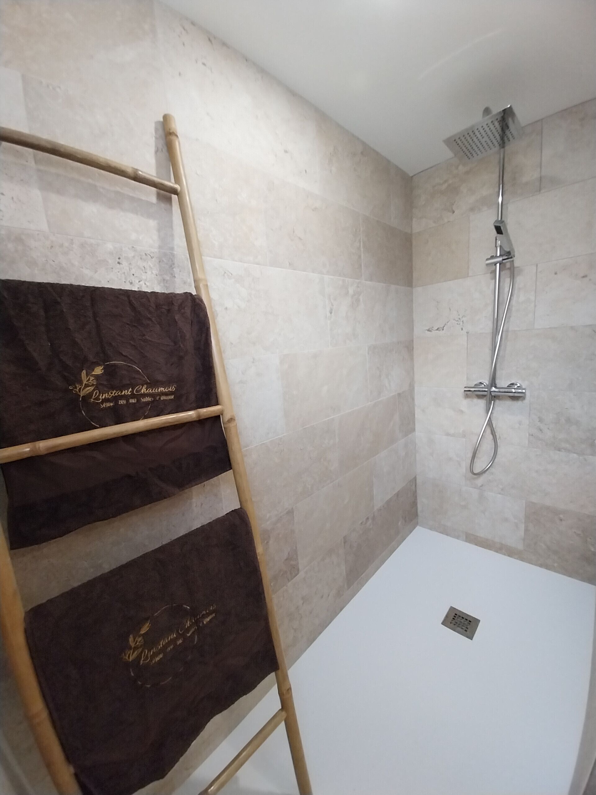 Une salle de bain avec une douche, un porte-serviettes avec des serviettes et une baignoire blanche.