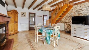 Un espace repas doté d’un plafond en bois, d’un mur en pierre et d’un escalier.