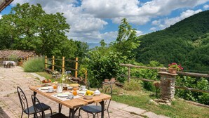 An outdoor dining area with a table set for breakfast, surrounded by lush greenery and a mountainous backdrop. - Wonderful  villa for 6 people with private pool, WIFI, TV and panoramic view, close to Florence (Gricignano)