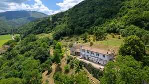 A white villa with a tiled roof, surrounded by lush greenery and hills. - Wonderful  villa for 6 people with private pool, WIFI, TV and panoramic view, close to Florence (Gricignano)