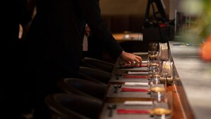 A person seated at a table with a laptop, a glass, and a menu. - Kin Hotel Dong Du (Ho Chi Minh City)