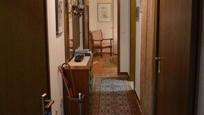 A hallway with a wooden ceiling, a patterned rug, a desk with a chair, and a door on the right. - Ferienwohnung Miezal, 1-4 Pers (Raesfeld)